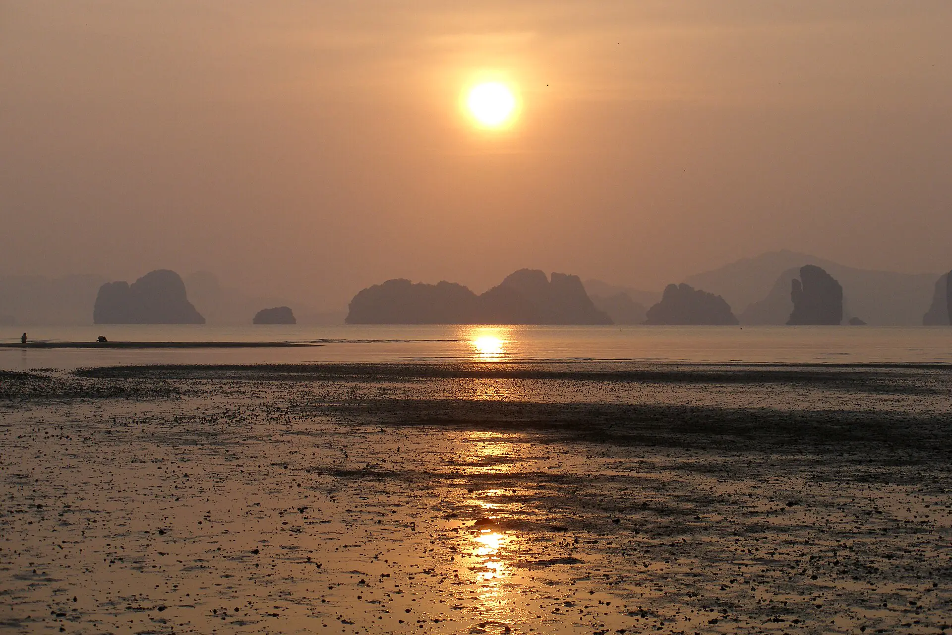 Limestone islands of Phang Nga Bay silhouetted against a golden sunrise